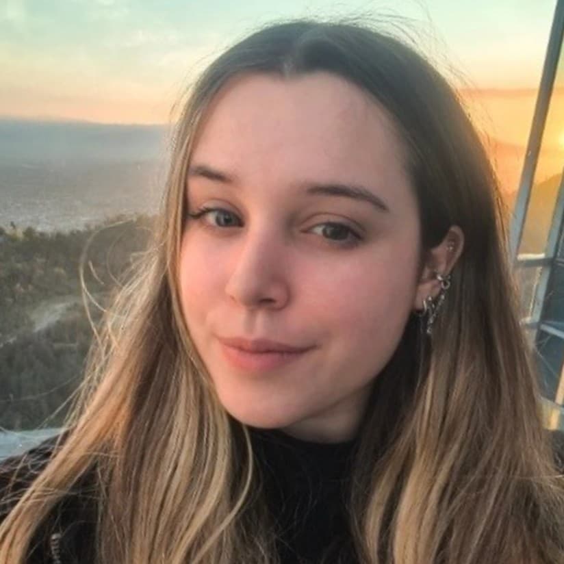 Jovem loira posa para foto em mirante com a cidade de Nova York ao fundo